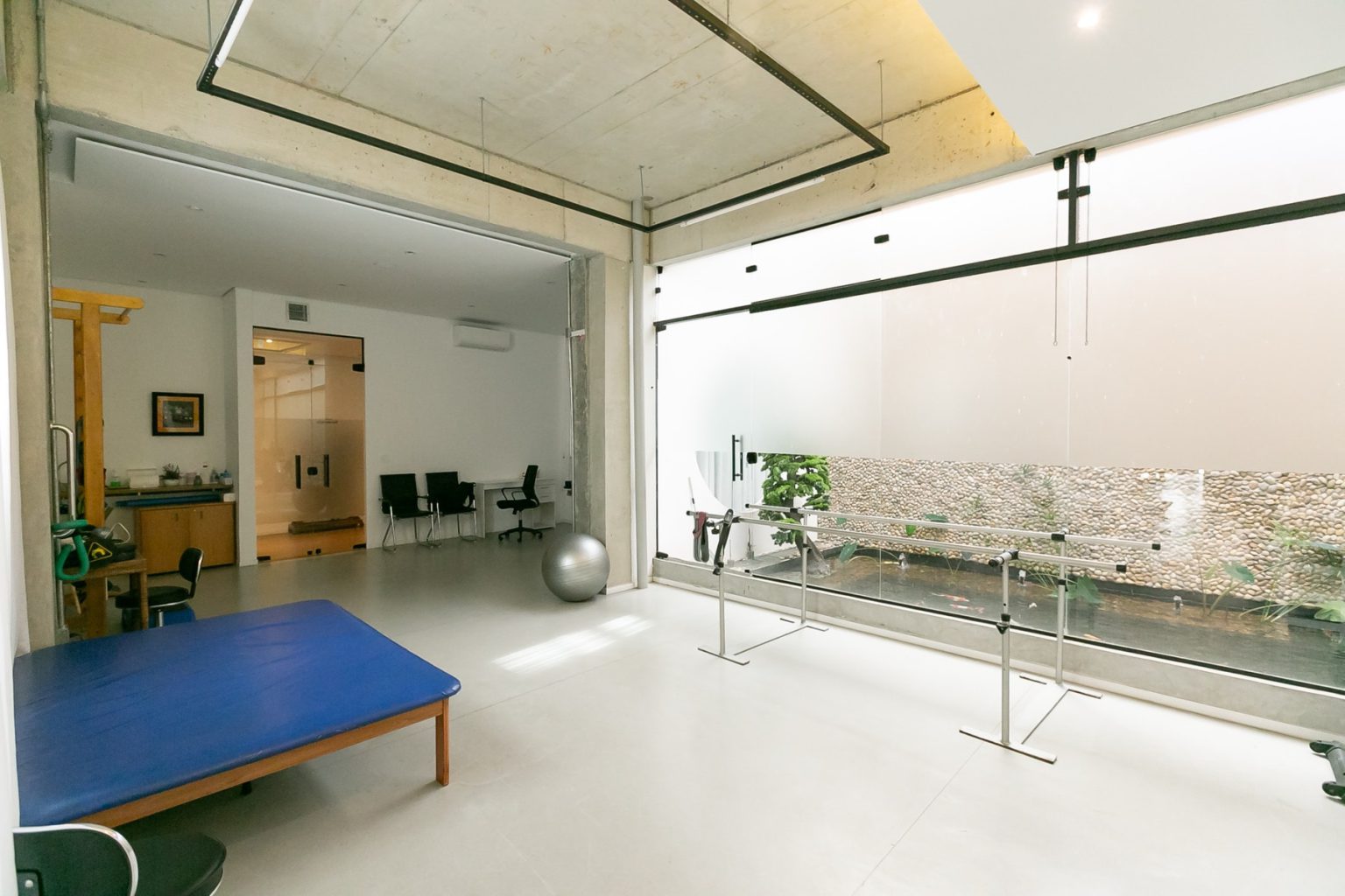 Sala de reabilitação com tablado de exercícios, bola suíça e barras paralelas
