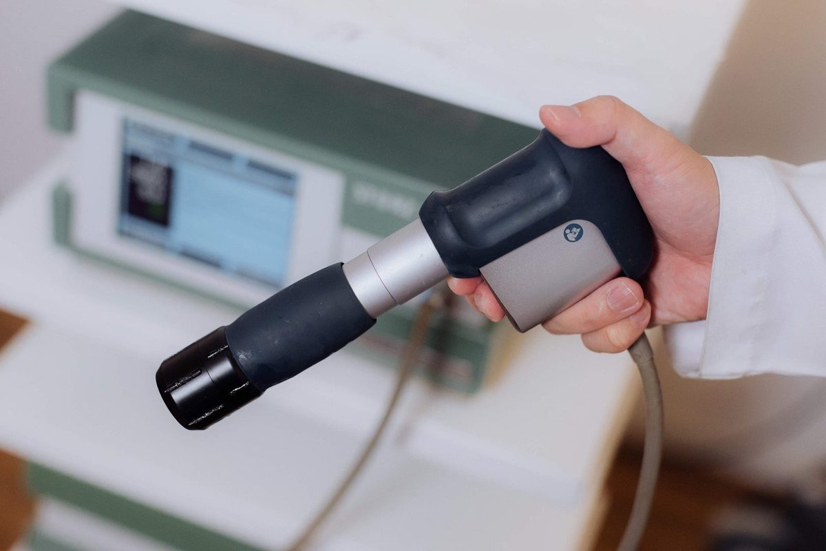 Mão do médico segurando o aplicador de ondas de choque radial