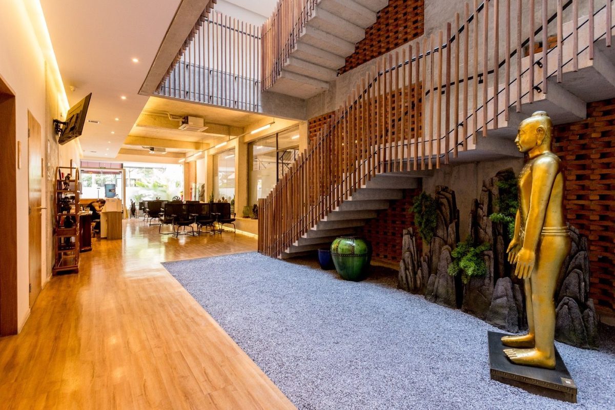 Hall da clínica com escada, jardim interno e uma estátua dourada