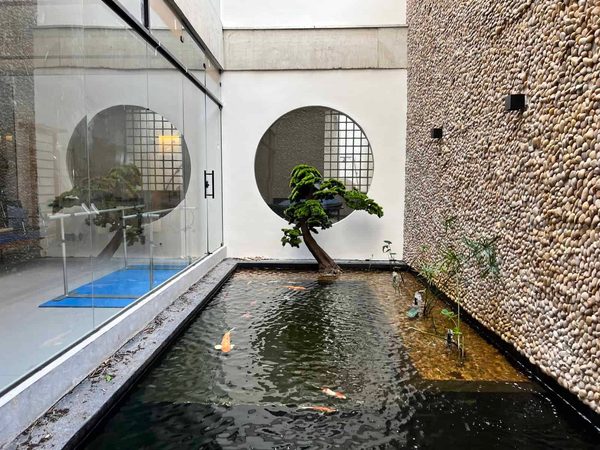 Jardim interno com janela redonda, bonsai e lago