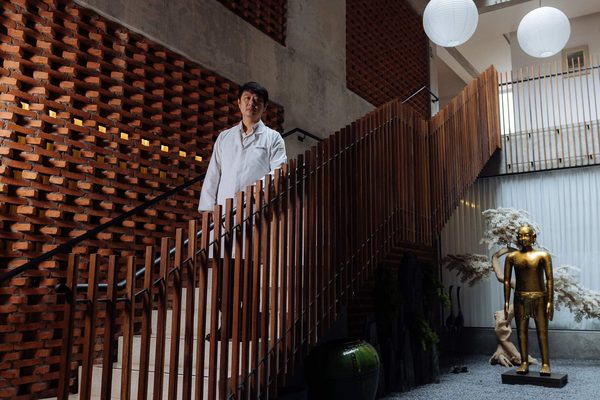 Dr. Marcus de jaleco na escada de ripas de madeira do átrio da clínica