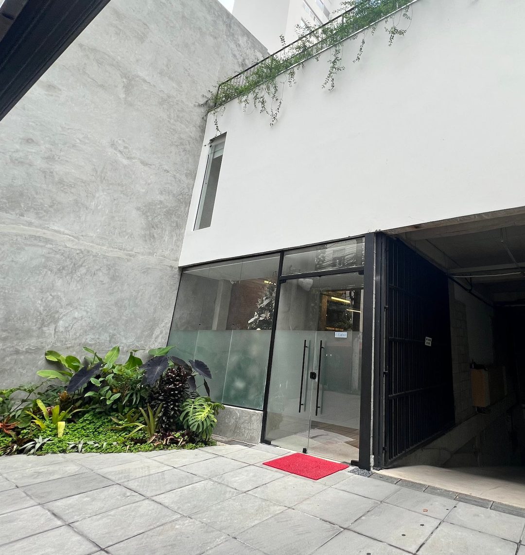 Entrada da clínica na Alameda Jaú, 687: portas de vidro, jardim à esquerda e portão da garagem à direita
