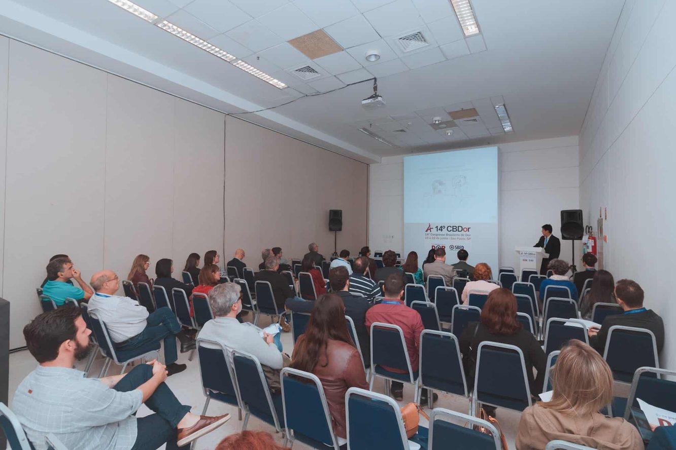 Sala do 14º Congresso Brasileiro de Dor, em São Paulo, em 2019: o Dr. Marcus Yu Bin Pai fala ao púlpito, ao fundo, e a plateia aparece em primeiro plano