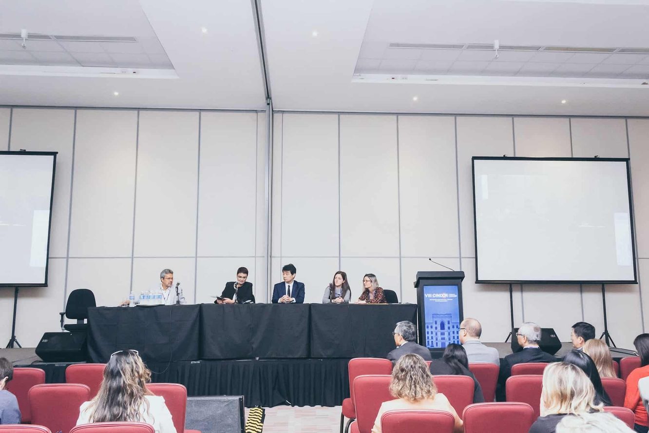 Plenária de discussão do VIII CINDOR: cinco pessoas sentadas à mesa, entre elas o Dr. Marcus Yu Bin Pai, com a plateia vista de costas