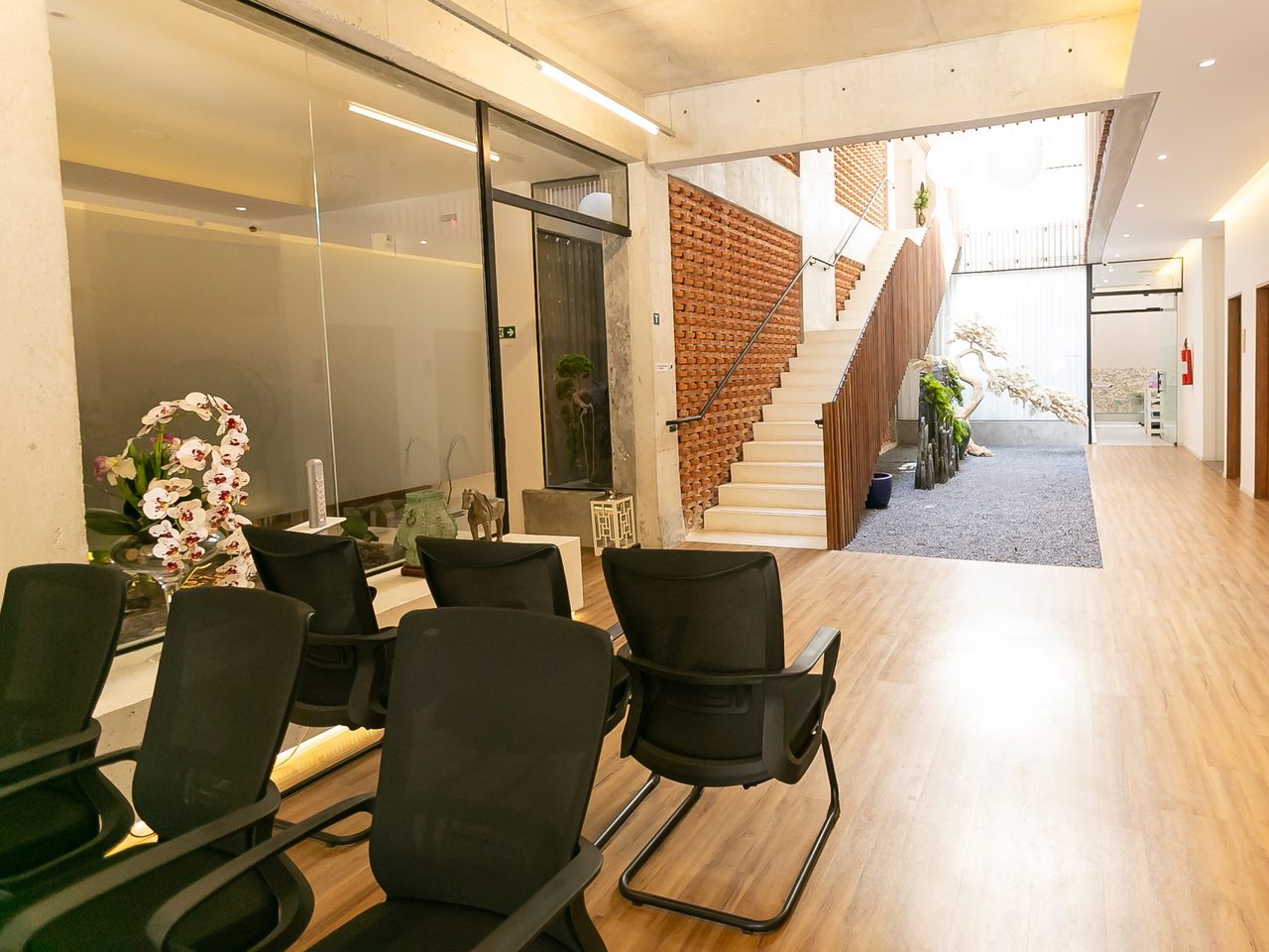 Sala de espera da clínica, com vista para o átrio, a escada e a parede de tijolos vazados